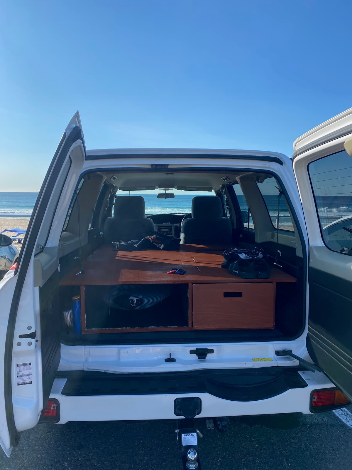 The completed bed platform with wooden drawer system in the Nissan Patrol, parked at the beach